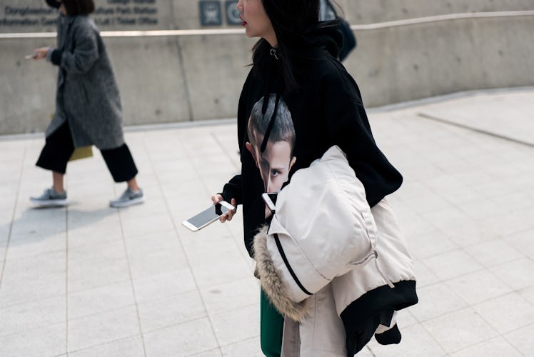 A woman wearing a black hoodie walking the streets during Seoul Fashion Week.