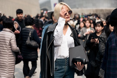 A woman wearing denim jeans, a white shirt and a black leather jacket walking the streets of Seoul.