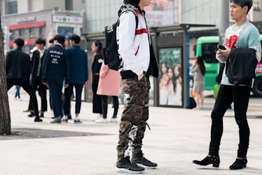 Two stylish individuals standing on a street during Seoul Fashion Week.