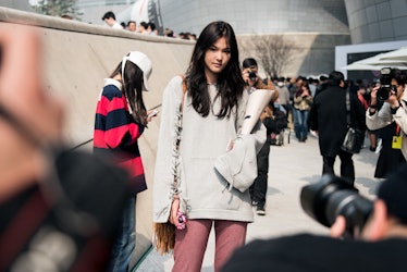 A girl wearing an off-white hoodie and pink pants while posing for a photo during Seoul Fashion Week...