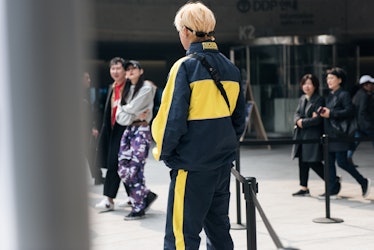 Street style star wearing a black-and-yellow tracksuit at Seoul Fashion Week.