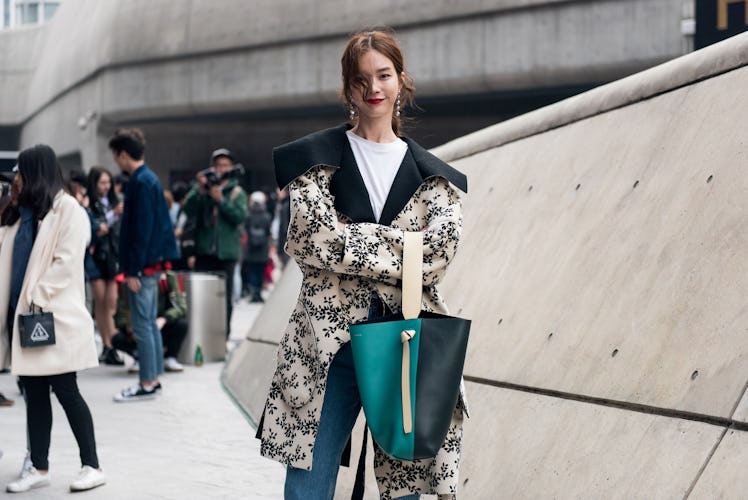 A girl in a black-and-white floral coat posing for a photo during Seoul Fashion Week.