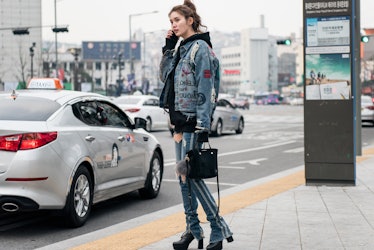 A girl wearing a denim outfit while talking on a phone during Seoul Fashion Week.