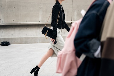 A girl in a white skirt, black ankle boots and a leather jacket walking the street of Seoul.