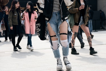 A person walking the street of Seoul in ripped jeans.