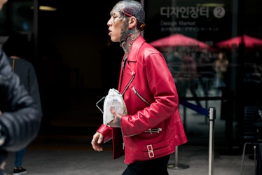 A bold man with a tattooed head in a red leather jacket walking the street of Seoul.