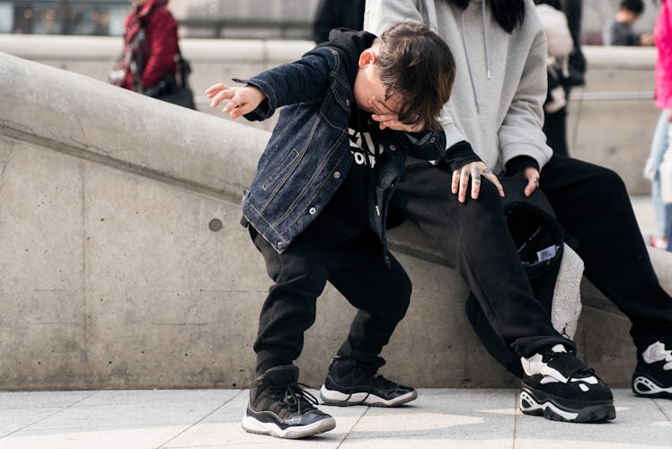 A toddler wearing a black tracksuit and a denim jacket during Seoul Fashion Week.