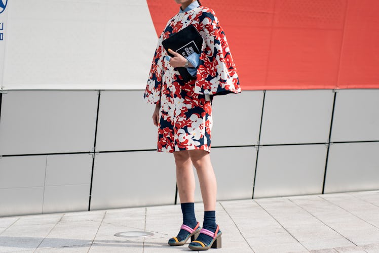 A woman in a floral dress with flare sleeves posing for a photo during Seoul Fashion Week.
