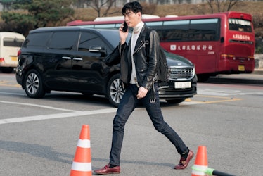 A trendy man using his phone while crossing the street in Seoul.