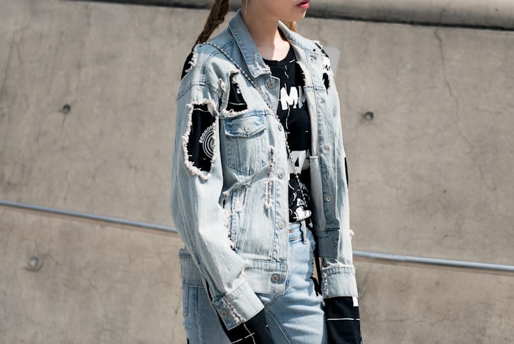 A girl dressed in a torn denim jacket and jeans, paired with a black t-shirt.