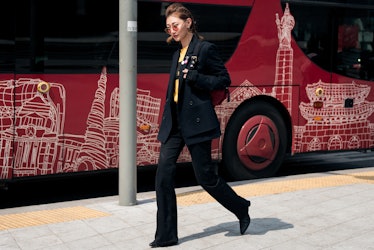 A woman dressed in a black suit and yellow t-shirt walking the street of Seoul.