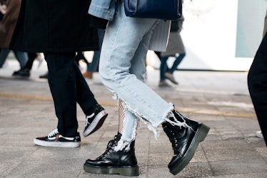A woman walking the street of Seoul in ripped jeans, fishnets and black chunky boots.