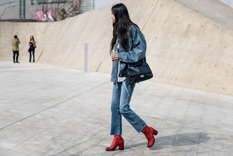 Stylish woman in denim and orange boots strolling Seoul's streets.