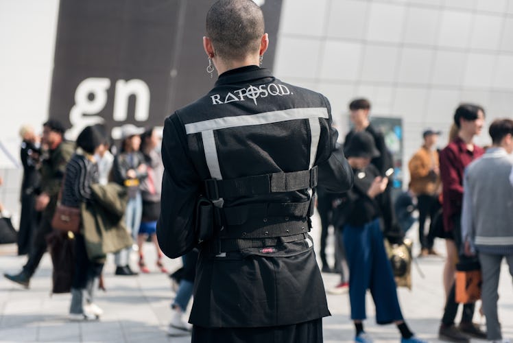 A man wearing a military uniform-inspired blazer on the street of Seoul.