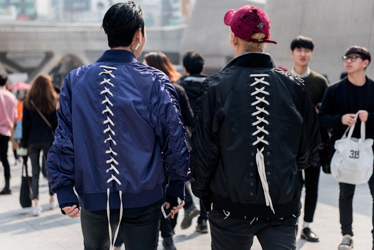 Two men in matching bomber jackets with laced backs walking the Seoul Street.