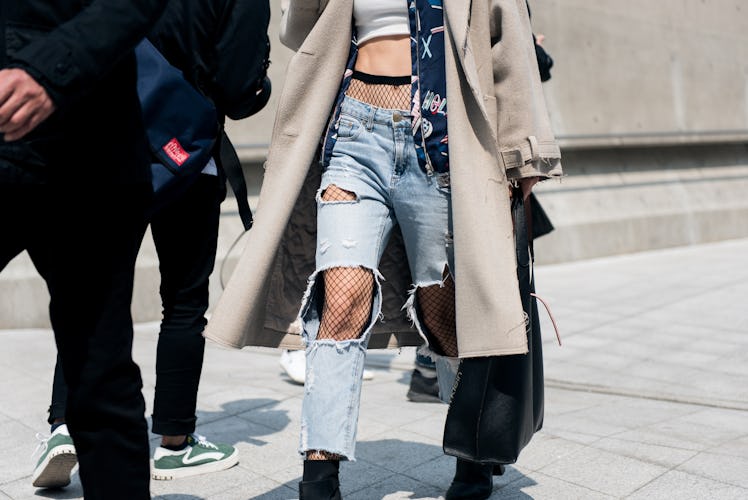 A woman wearing ripped jeans and fishnets during Seoul Fashion Week