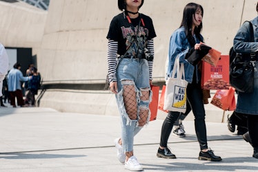 A woman sporting ripped jeans, fishnets and a band-tee on the street of Seoul.