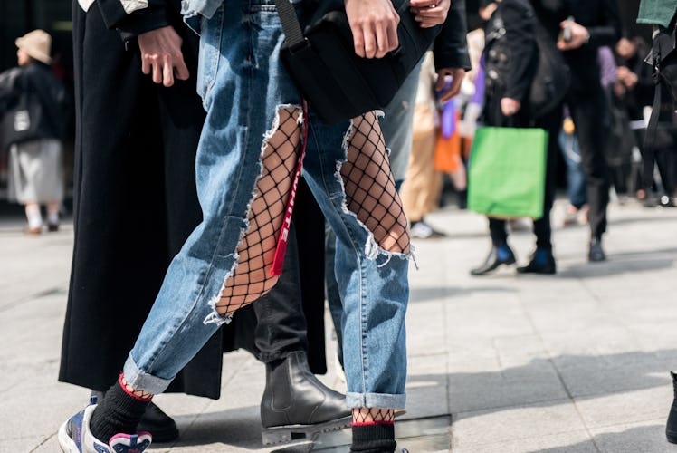 A person walking the street in ripped jeans and fishnets during Seoul Fashion Week