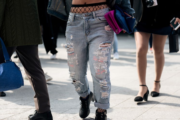 A person wearing ripped jeans paired with fishnets