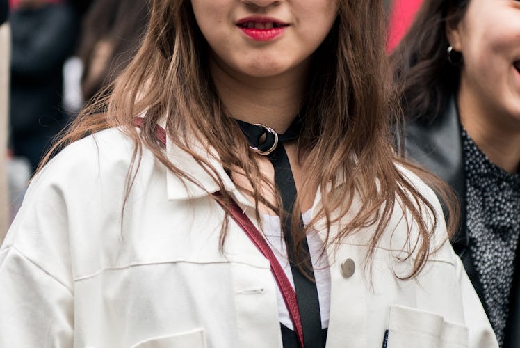 A woman wearing a white shirt and a black choker necklace on the street of Seoul.