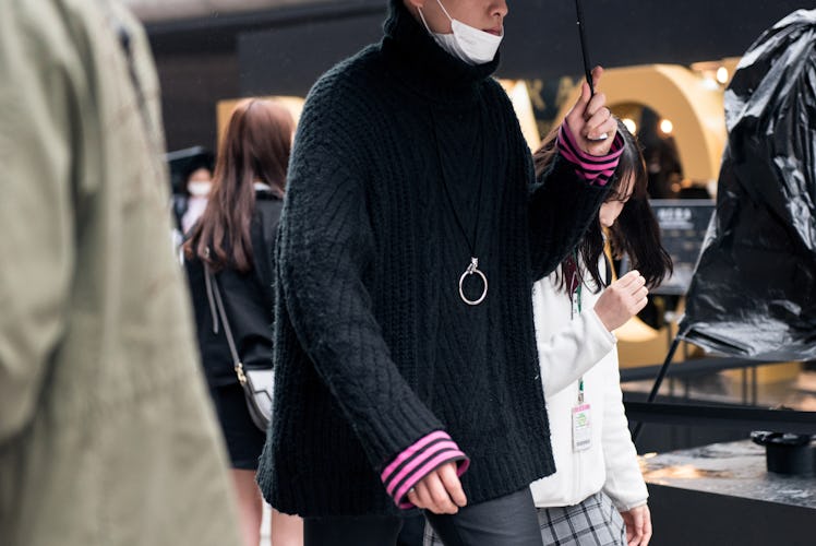 A man walking the street in a black jacket with punk details