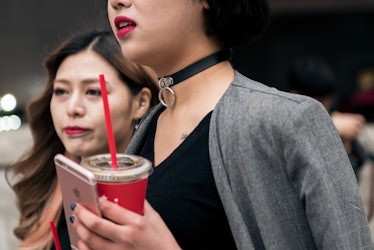 South Korea’s street style star wearing a choker with chain detail holding her phone and drink