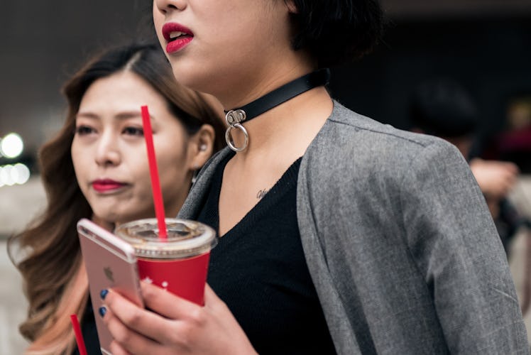 South Korea’s street style star wearing a choker with chain detail holding her phone and drink