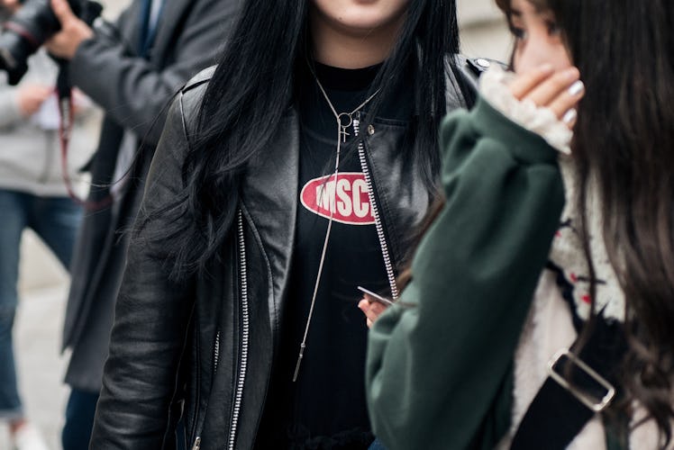 A woman wearing a black leather jacket, a black t-shirt and a chain necklace
