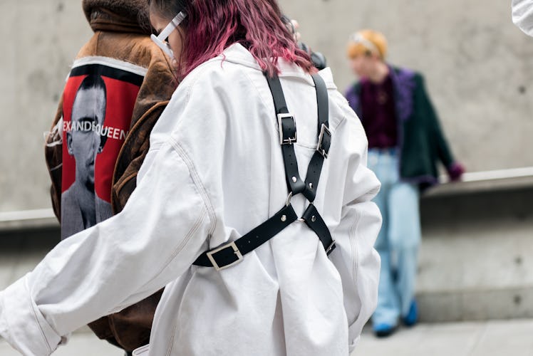 A woman wearing a white shirt and a black punk harness