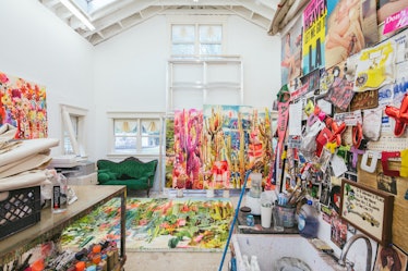 The inside of Rosson Crow studio with a green couch, paintings and illustrations on a wall