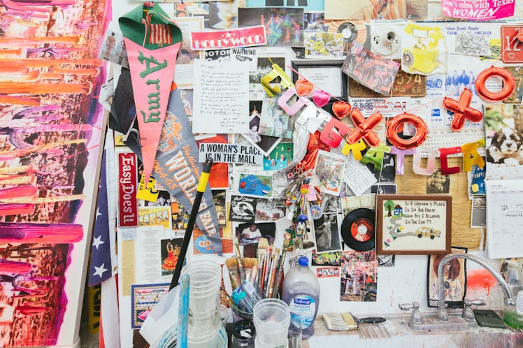 The inside of Rosson Crow studio with various stickers and illustrations on a wall and brushes on a ...