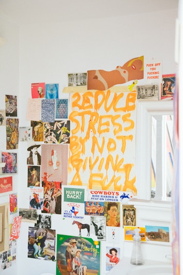 A white wall decorated with various posters, photographs and graffiti art