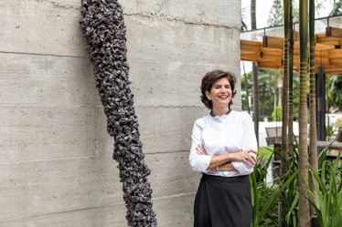 Fernanda Feitosa standing next to the piece of art that looks like a scepter leaning against her hou...