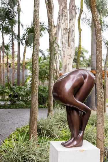 A statue of a person bent over grabbing their legs, with no head visible in the garden 