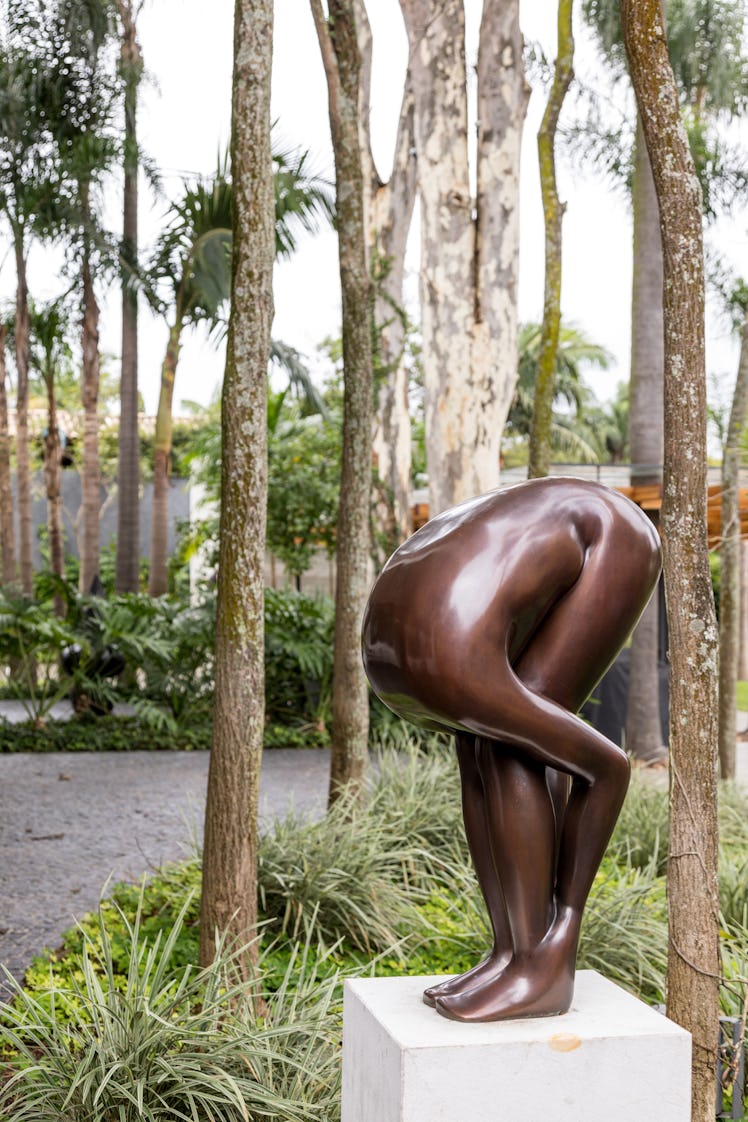 A statue of a person bent over grabbing their legs, with no head visible in the garden 