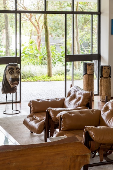 Fernanda Feitosa's living room with brown leather couches and tribal statues 