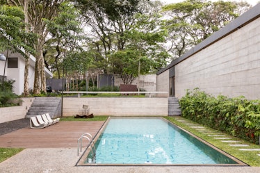 A narrow pool with white chairs around in Fernanda Feitosa's São Paulo home