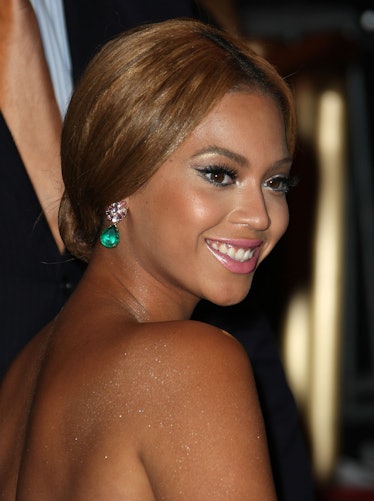 Beyoncé at the met gala with her hair in a low chignon and green drop earrings