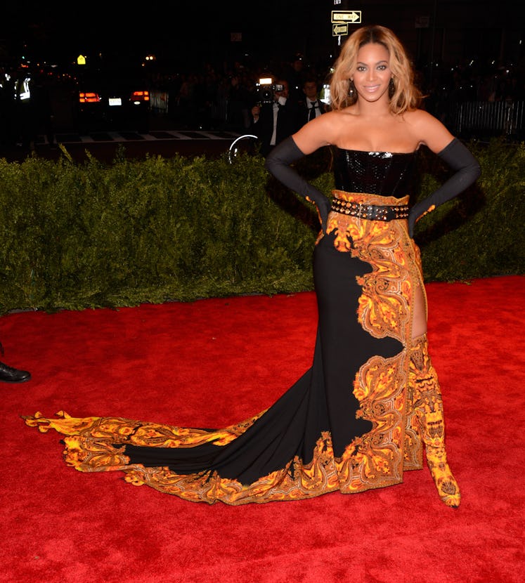 Beyoncé in a black strapless gowns with rococo flames and matching thigh high boots at the met gala