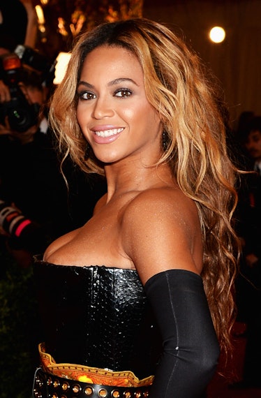 Beyoncé in a black strapless gowns with rococo flames and matching thigh high boots at the met gala