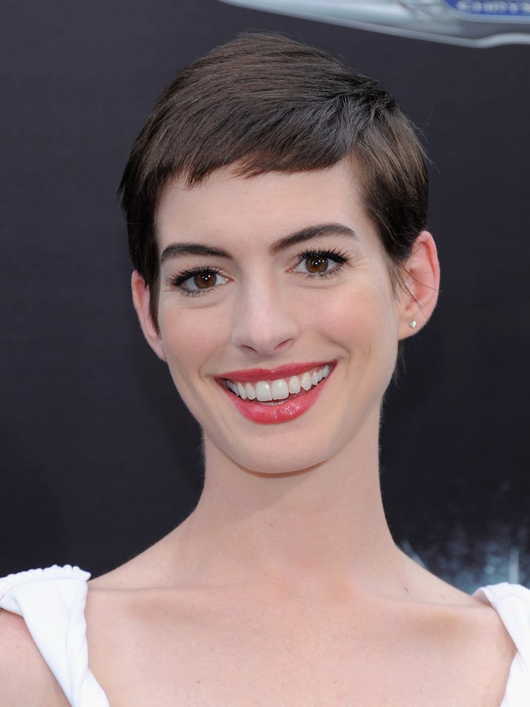 Anne Hathaway with a short pixie haircut in a white dress at a red carpet event