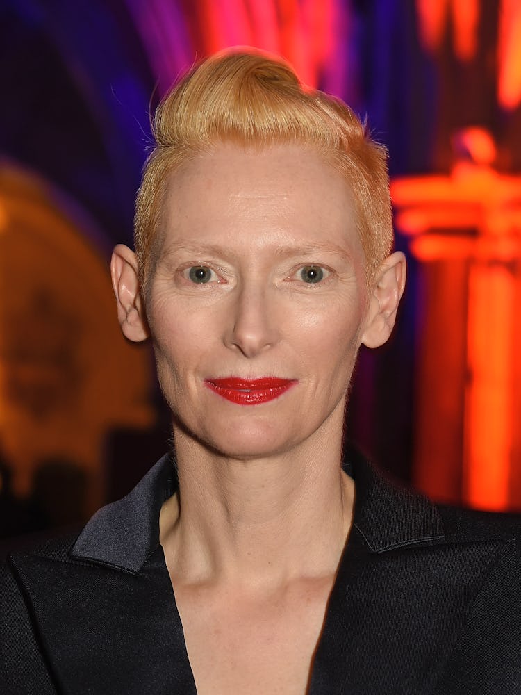 Tilda Swinton with a short haircut in a black top wearing red lipstick at a red carpet event