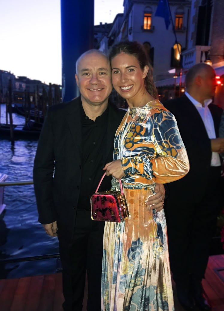 Colby Mugrabi in an orange-blue velvet dress posing with Damien Hirst in a black suit