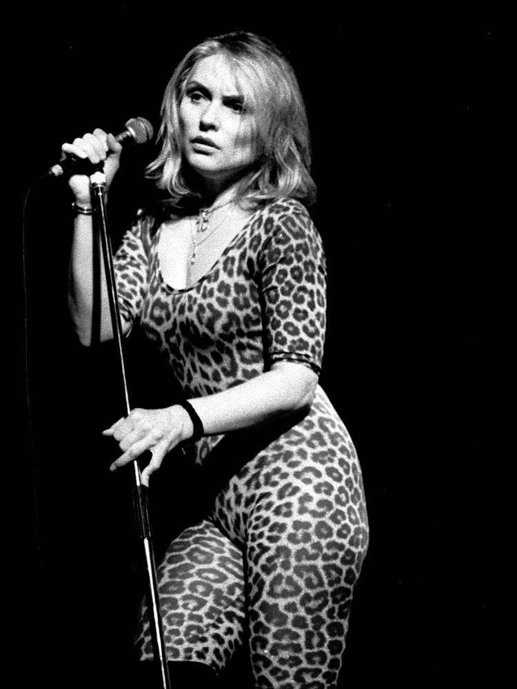 Debbie Harry performing in a leopard print jumpsuit while holding a microphone stand