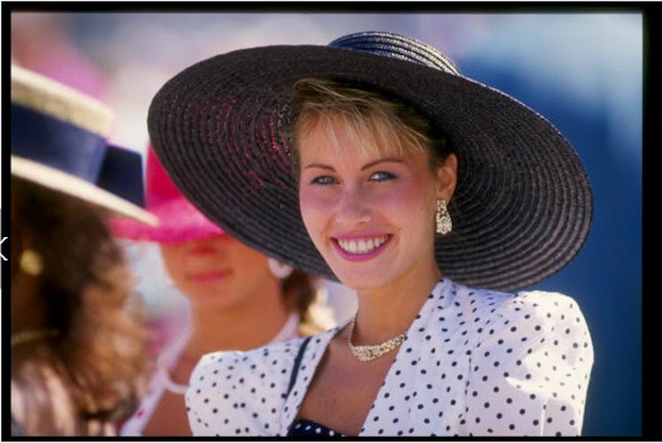 A smiling blonde woman in a white-black polka dot dress and a large black hat at the Kentucky Derby ...