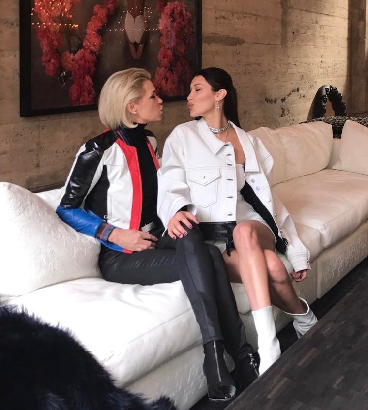 Yolanda Hadid in a black-white leather jacket sitting and blowing a kiss to Bella Hadid in a white j...