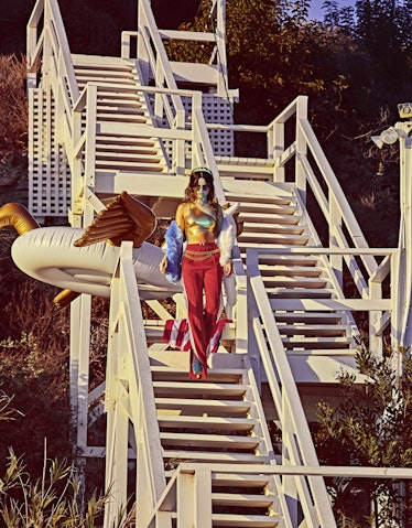 Selena Gomez going down the stairs on a beach dressed in an outfit with US flag colors 