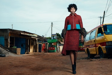 Naomi Campbell walking in Ghana while wearing a burgundy set with bright blue pockets