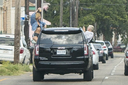 Kristen Stewart and Stella Maxwell leaning out of a moving car and taking photos of each other