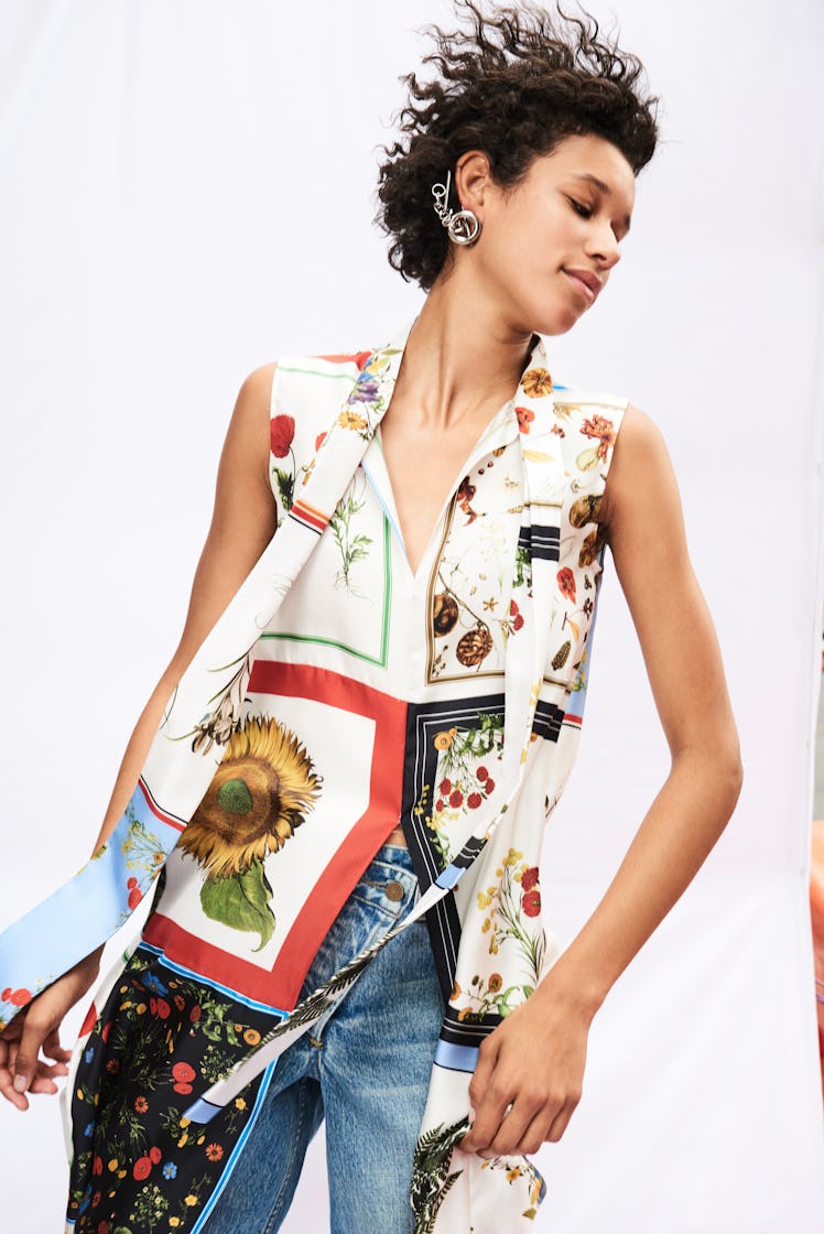 A female model posing while wearing a silk scarf-print sleeveless blouse